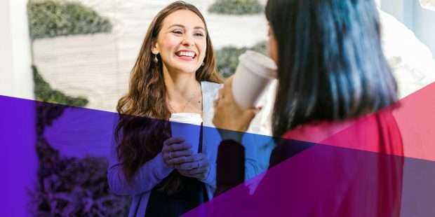 a woman holding a coffee chatting with a colleague